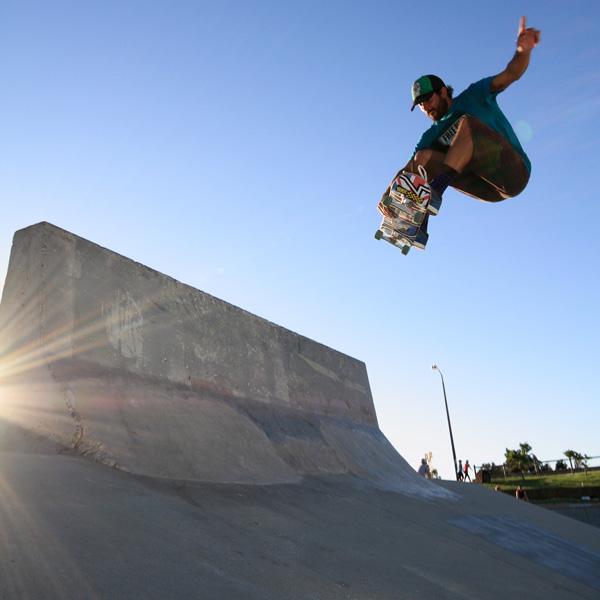 A concrete construction barrier is used as a skateboard ramp with a person on a skateboard mid-jump